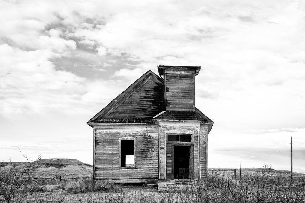 Black and white photograph of the old Taiban Presbyterian Church, built 1908 near Ft. Sumner, New Mexico. The remains of the church stand on the western edge of the Llano Estacado surrounded by caprock formations. Active into the 1930s, the church sat vacant since 1960. In 2006 vandals broke out doors and windows leaving the structure in ruins.