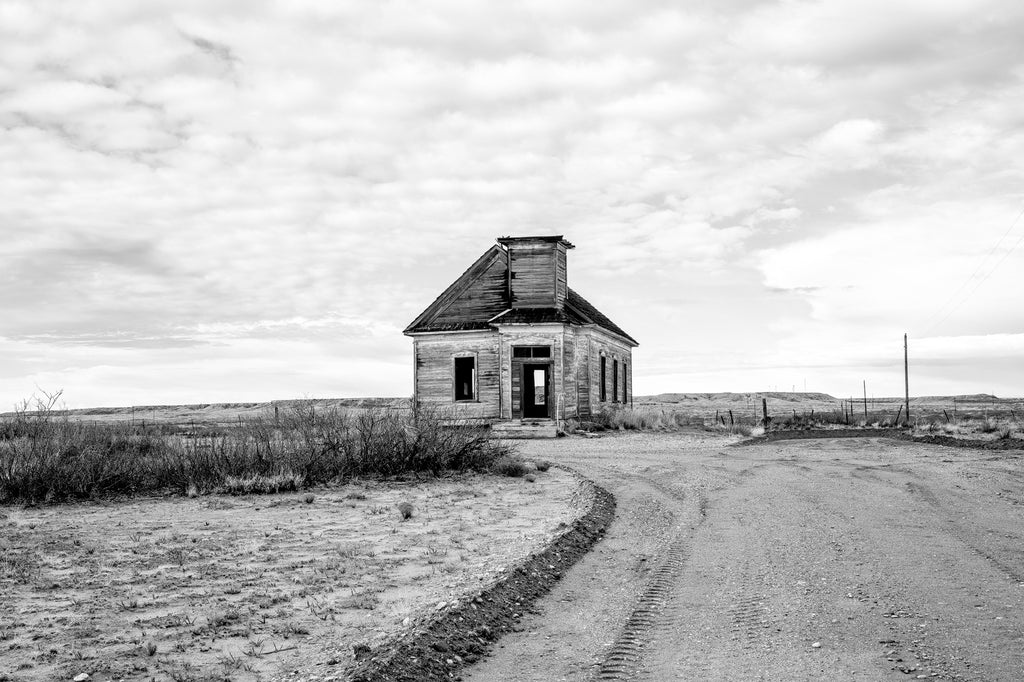 Black and white photograph of the old Taiban Presbyterian Church, built 1908 near Ft. Sumner, New Mexico. The ruins of the church sit under a vast sky surrounded by caprock formations on the western edge of the Llano Estacado. Active through the 1930s, the church has been unused and vacant since about 1960. Vandals destroyed the windows in 2006.