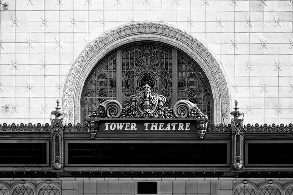 Black and white photograph of the ornate marquee of the historic 1927 Tower Theatre in downtown Los Angeles. The theatre was the first to play talking pictures in Los Angeles and closed as a theatre in 1988. Currently holds a retail store.