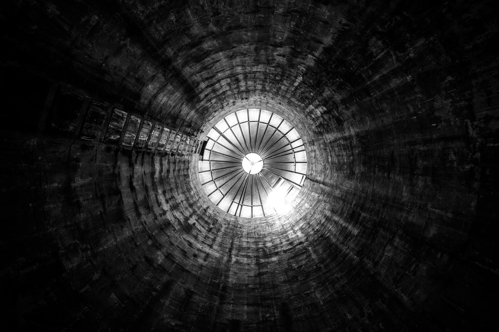 Black and white photograph looking up at the interior of a grain silo on a former dairy farm.