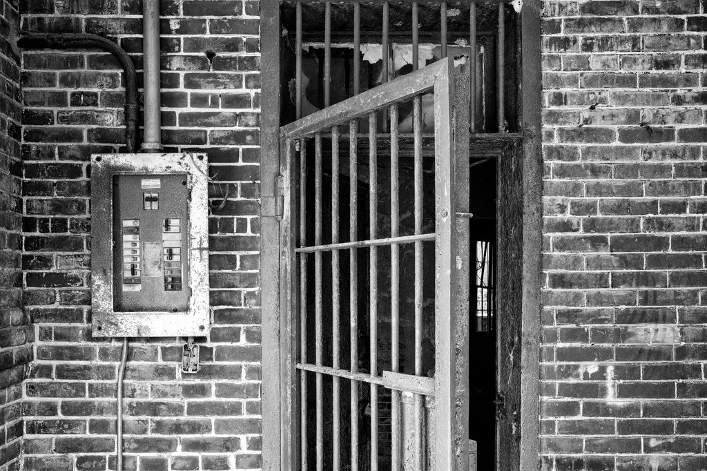 Black and white photograph of the front door with bars leading inside the abandoned 1894 jail in Tunica, Mississippi.