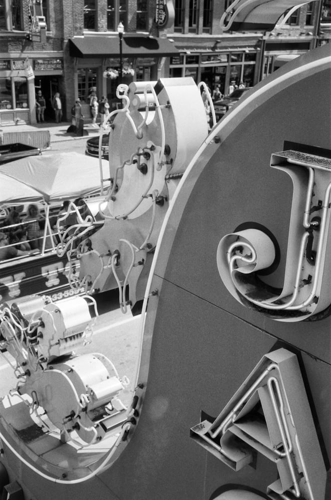 Black and white photograph of Jack's BBQ sign with a view of lower Broadway in Nashville. This photograph was shot on 35mm Ilford Delta 400 black and white film. Note that your print will contain the characteristic film grain evident in film stock, which most people consider a desirable effect of analog film photography.
