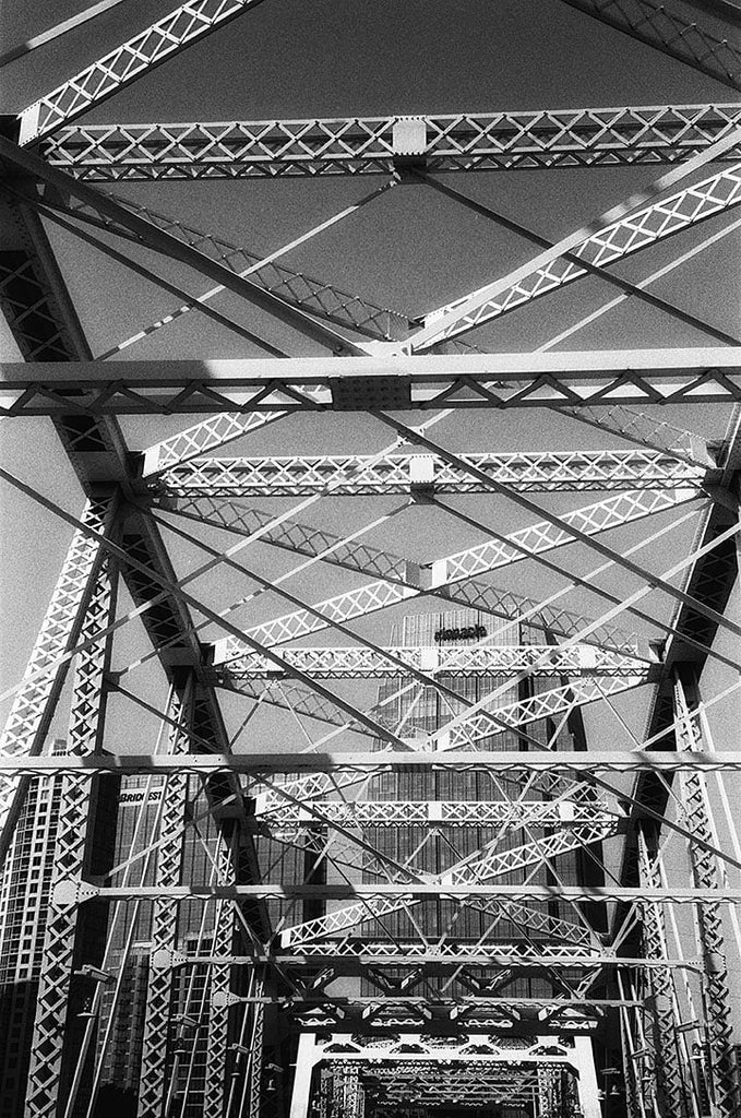 Black and white photograph of the John Seigenthaler Pedestrian Bridge in Nashville, seen from the point of view of someone walking across the river.