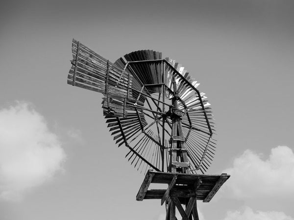 Black and white photograph of a historic wooden windmill in the desert of west Texas near Pecos.