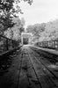 Black and white photograph of an old one-lane bridge with wooden roadbed. This photograph was shot on 35mm Ilford HP5 film, which gives it a grainy look, intrinsic to that brand of film stock.