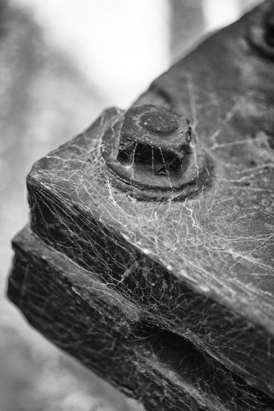 Black and white photograph of a steel corner with a large bolt at Sloss Furnaces in Birmingham, Alabama covered in cob webs.