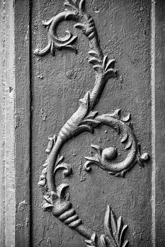 Black and white photograph of an antique cast iron flower architectural decoration, found on the exterior of an old storefront building in a small town.