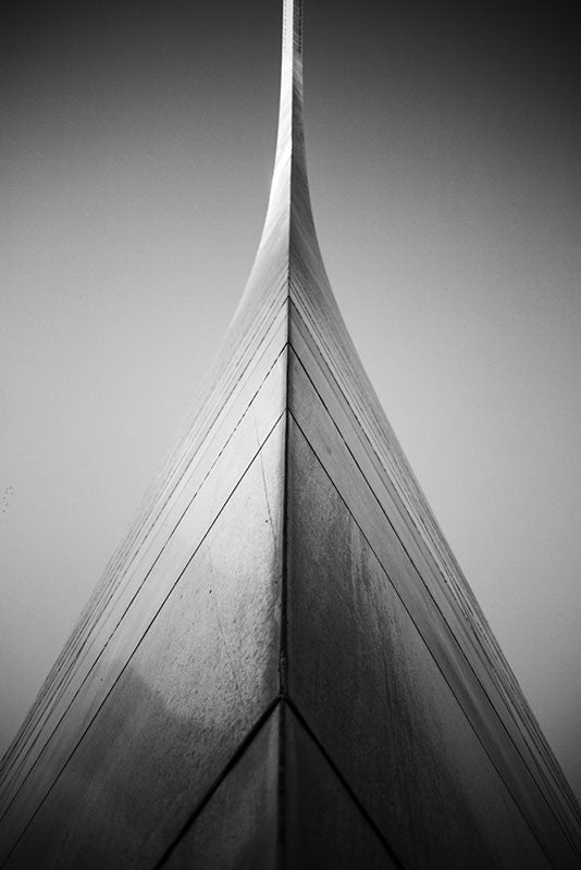 Black and white photograph of the famous St. Louis Gateway Arch, centered in the frame as it swoops away into the sky. 