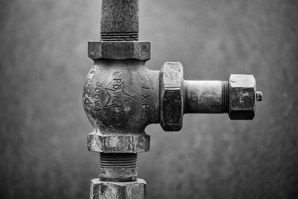 Black and white industrial photograph of a pipe connection on an antique machine.