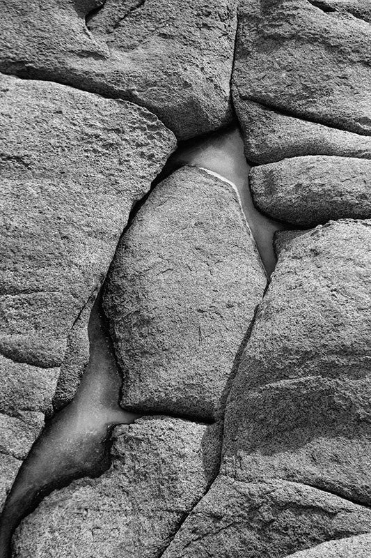 Black and white photograph of a frozen tide pool amongst the rugged rocks of the Maine seacoast.