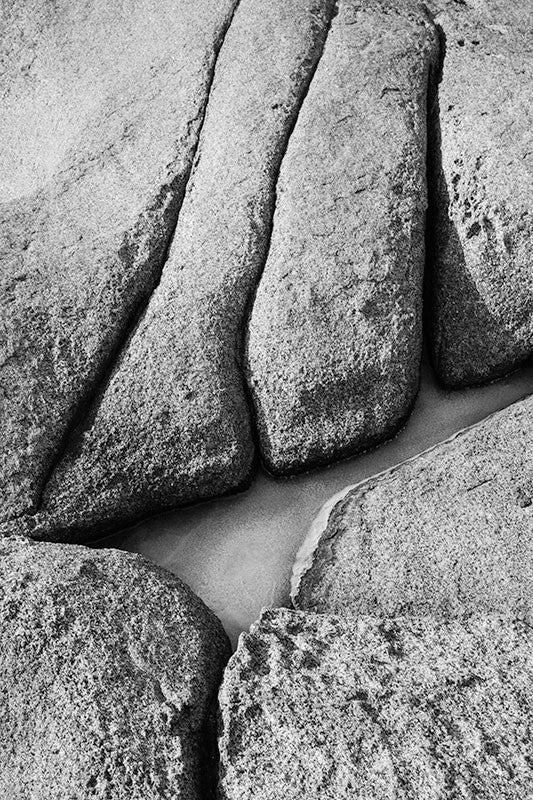 Black and white photograph of a frozen tide pool amongst the rugged rocks of the Maine seacoast.