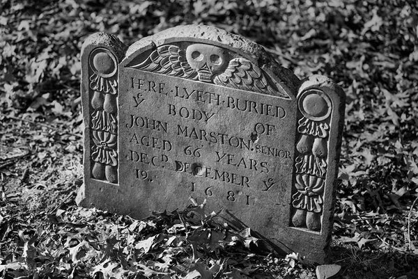 Black and white photograph of an original historic 1681 gravestone for John Marston buried in the Old Burying Point cemetery in Salem, Massachusetts.