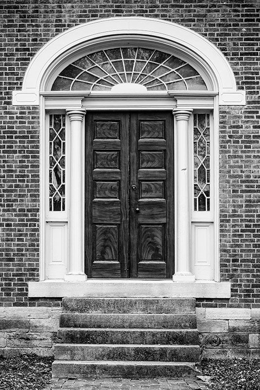 Black and white photograph of the front door of the historic Carter House in Franklin, Tennessee. The house and its property was a site of bloody fighting during the battle of Franklin, and bullet holes can still be seen in the house and outbuildings. A bullet scar can be seen in the woodwork next to this old door.
