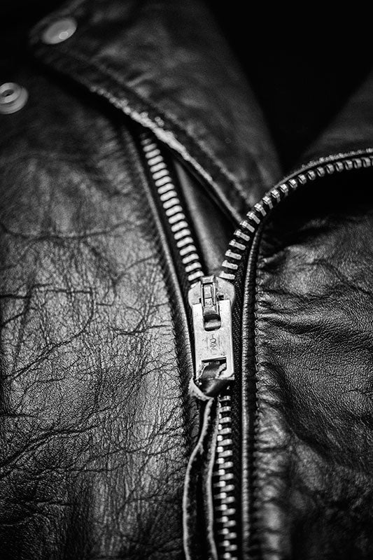 Black and white fine art photograph of a black leather jacket once owned and worn by Elvis Presley, as seen in a museum exhibit.