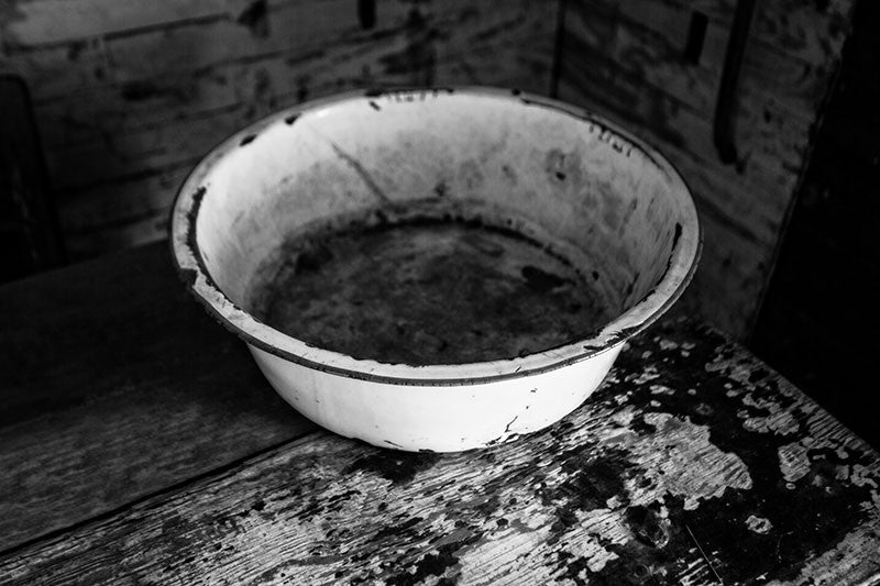 Black and white photograph of a wash basin on a table inside the home of the late blues musician Sleepy John Estes in Brownsville, Tennessee. The small shack where Estes lived has been preserved and relocated to a visitors center near the schoolhouse of Tina Turner, who also hails from Brownsville.