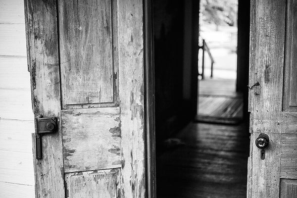 Black and white photograph of French doors on the front of an old Cajun house in Lafayette, Louisiana.