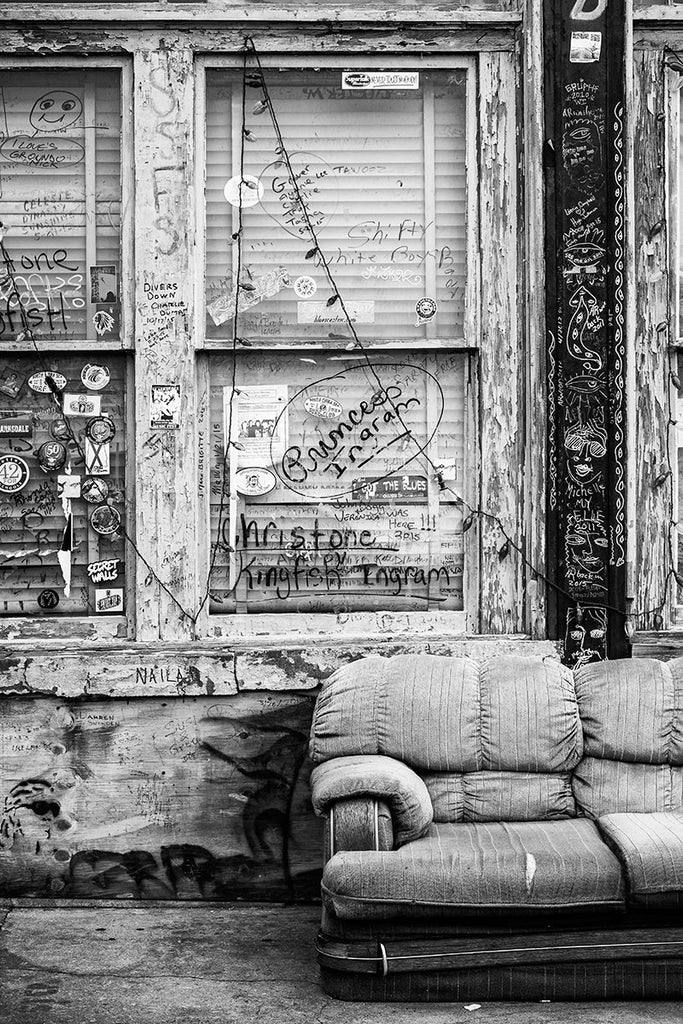 Black and white photograph of the front porch of a downtown Clarksdale, Mississippi, with an old sofa and lots of graffiti.