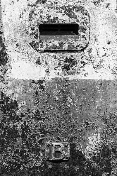 Black and white detail photograph of the beautifully textured, cracked and peeling side of an old train car.