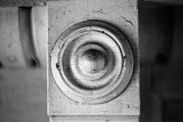Black and white detail photo of an antique wooden fireplace mantel from an old southern home.