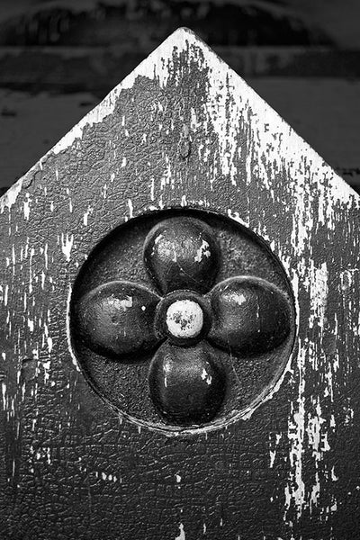 Black and white photo of an antique wooden banister post, with peeling paint and craquelure texture.