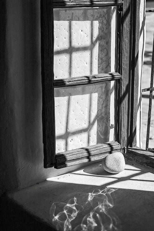 Black and white photograph of a 260-year-old window, propped open with a stone, at The Spanish Governor's Palace in San Antonio, Texas.
