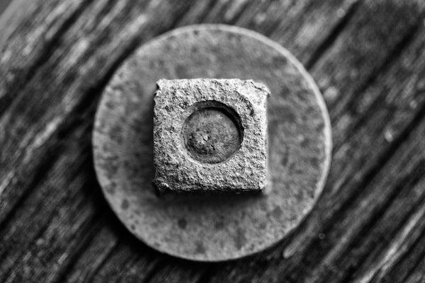 Black and white photograph composition of rusty hardware set against a piece of rusty wood. This macro photo was made from an antique piece of farm equipment.