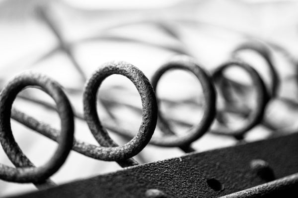 Black and white abstract photograph of rusty metal loops on an antique piece of farm equipment.