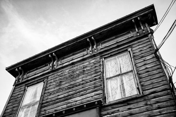 Black and white photograph of the Italianate roofline of the weathered wooden 1880s-era drugstore in St. Augustine, Florida. The old Speissegger Drugstore in St. Augustine's old town was built as part of an upscale Victorian development in 1886 and operated as a drugstore / pharmacy until the 1960s. It's the last remaining structure from that development.