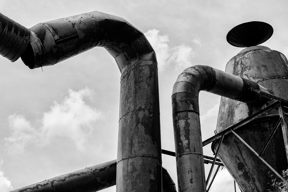 Black and white photograph of a rusty, derelict piece of industrial machinery.