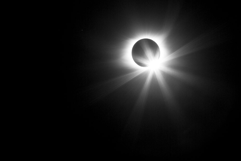 Black and white photograph of the sun just emerging with a burst of light from behind the moon in the great solar eclipse of 2017.
