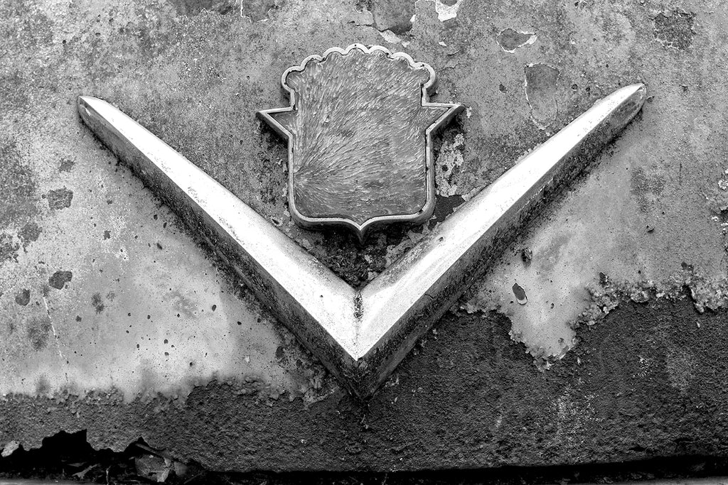 Black and white fine art detail photograph of textured, rusty paint and chrome on a classic antique American car hood ornament