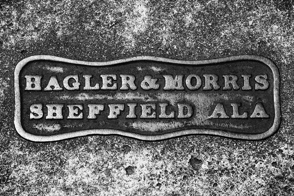 Black and white photograph of an old sidewalk marker that reads "Hagler & Morris Sheffield Ala."