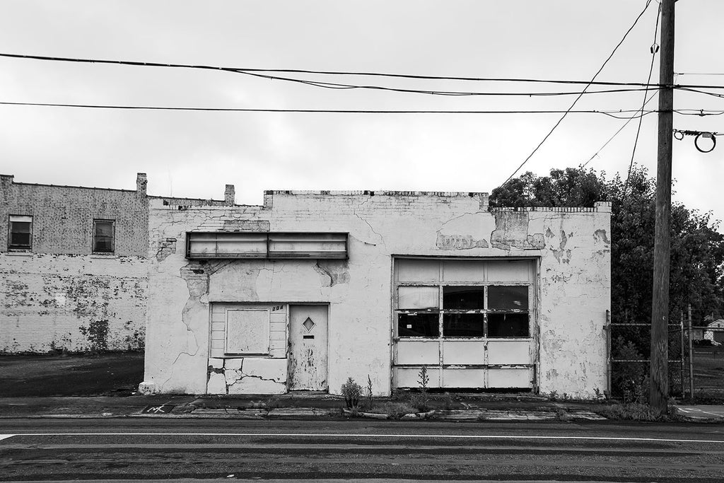Black and white photograph of an abandoned service station painted all white, in a small town in North Carolina.