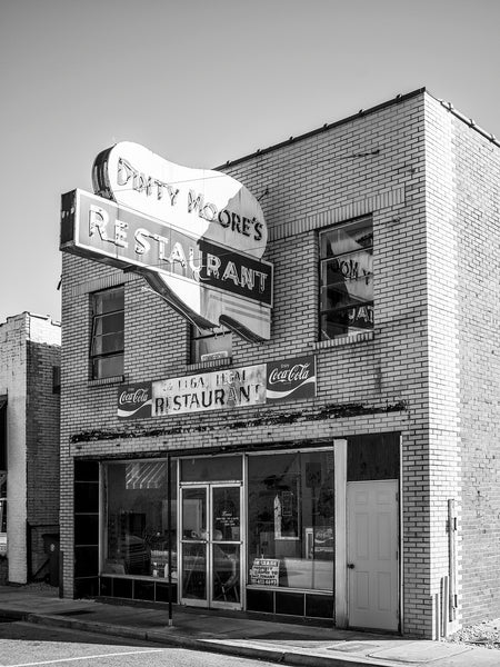 Black and white photograph of a vintage Dinty Moore Restaurant sign in McMinnville, Tennessee. Subsequent businesses left the sign intact but the building is now vacant.