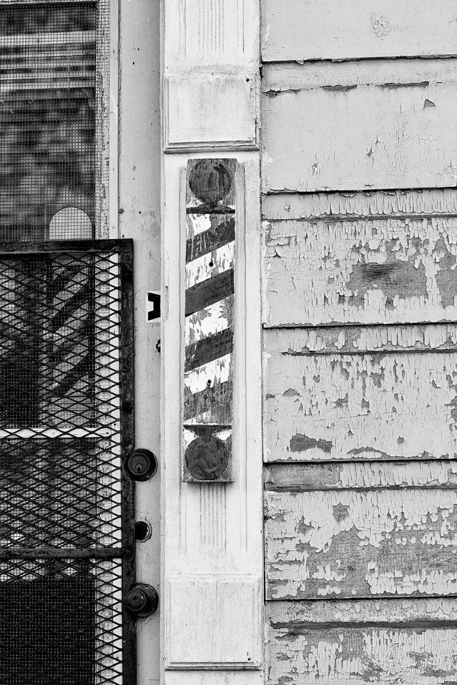 Black and white photograph of a crusty, peeling barber shop sign in the Tremé neighborhood of New Orleans.
