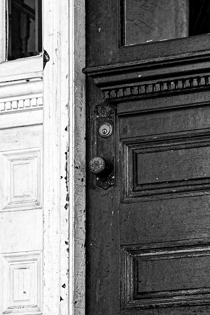 Black and white architectural detail photograph of the heavily painted door of an old boarding house.