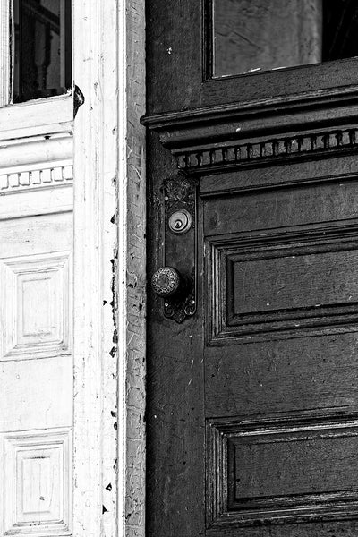 Black and white architectural detail photograph of the heavily painted door of an old boarding house. 