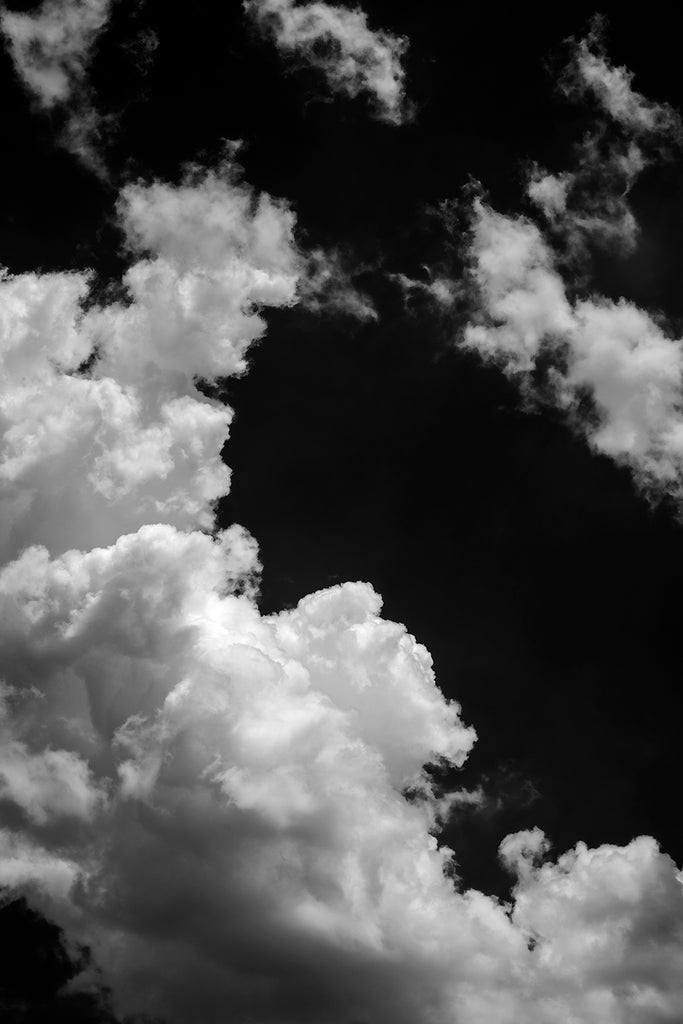 Black and white photograph of a tall white cloud bank set against the deep blue sky of a summer day.