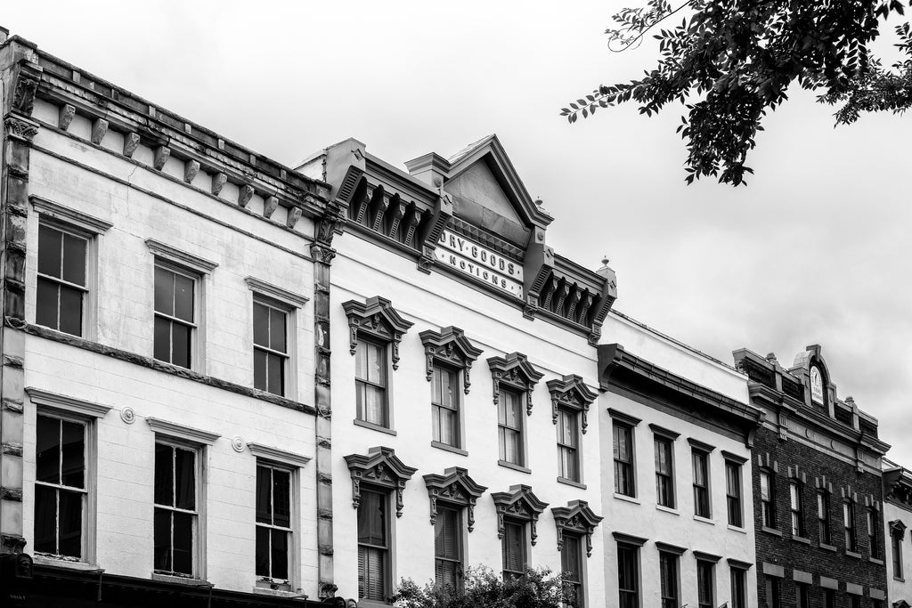 Black and white photograph of historic commercial storefront architecture with fancy pressed metal molding, found near the old Charleston City Market on Meeting Street. The sign reads "Dry Goods - Notions."