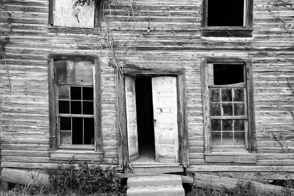 Black and white photograph of the front of a crooked, old, wooden building that may have been a Mason Lodge, found in a ghost town in the deep South.