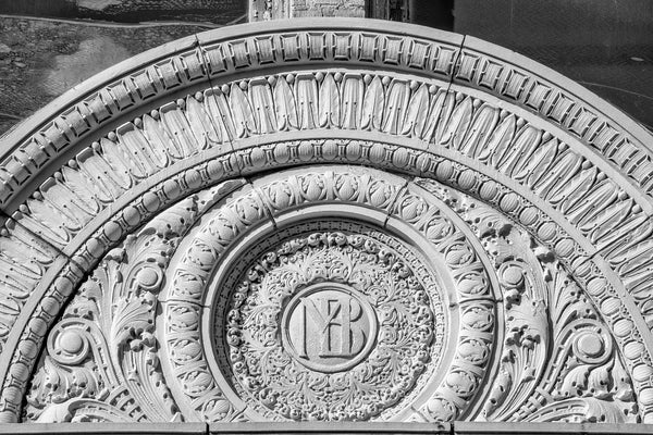 Black and white photograph of an ornate carved antique sign for a bank building now vacant.