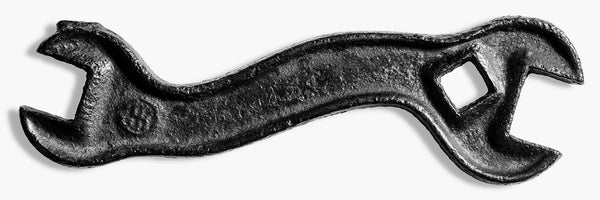 Striking black and white detail photograph of an antique International Harvester S-shaped tractor wrench. Scratched into the rusty handle is the name of the tool's former owner "Jared S." This panoramic wide-aspect print is designed to be a stunning conversation piece, appearing dimensional as it dominates a wall, revealing a landscape of rusty detail.