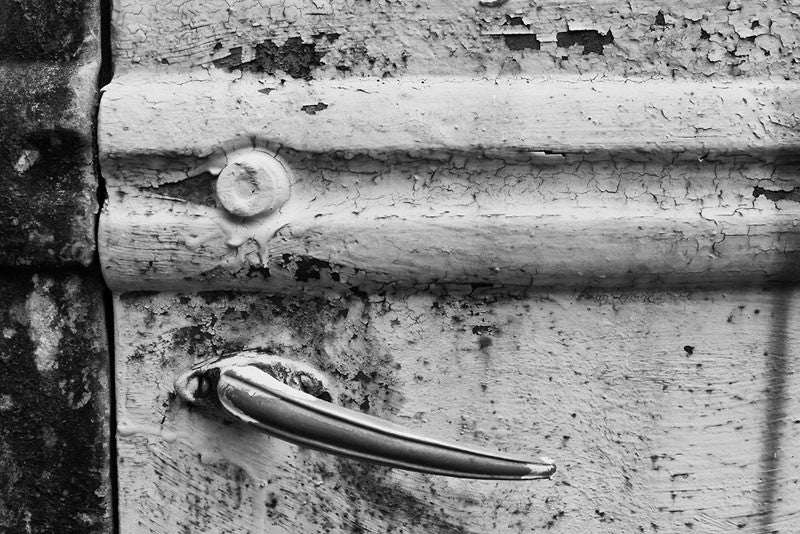 Black and white fine art photograph of an old truck door that has been hand-painted with a heavy coat of yellow paint.