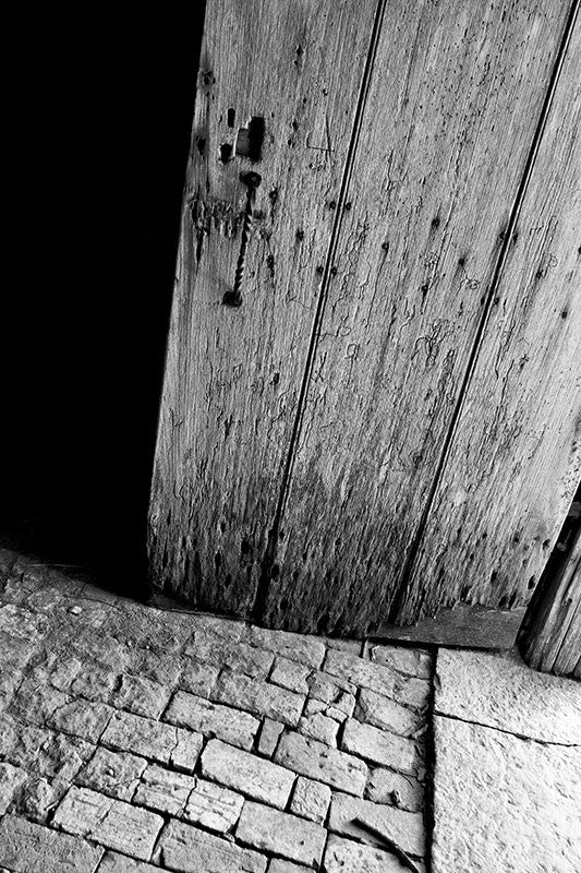 Black and white photograph of the old worm-eaten wooden door and stone floor of the Carnton smokehouse, an outbuilding that was constructed in 1815.