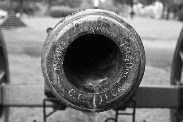Black and white photograph of the muzzle of a civil war cannon at Stones River National Military Cemetery in Murfreesboro, Tennessee. The engraving reads "No. 390. Revere Copper Co. 1240 lbs. C.C. 1864."