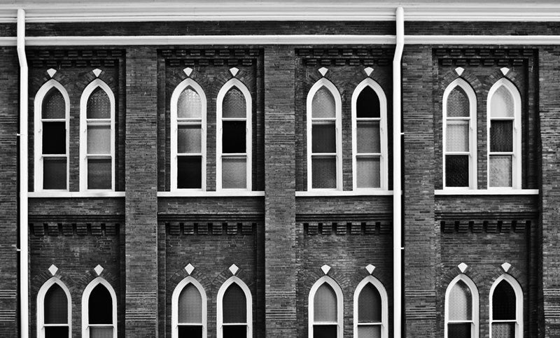 Black and white photograph of the windows of the historic Ryman Auditorium in Nashville, Tennessee. Famous as the home of the Grand Ole Opry from the 1940s to the 1970s, the building started in 1892 as the Union Gospel Tabernacle, hence the church-like style of the windows and the nick name "mother church of country music." The Ryman continues as one of the nation's most famous and admired performance venues.