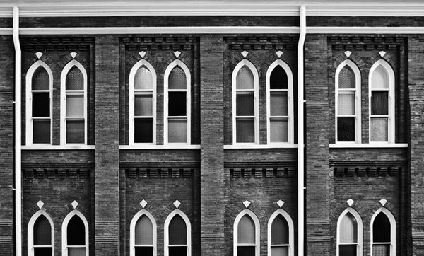 Black and white photograph of the windows of the historic Ryman Auditorium in Nashville, Tennessee. Famous as the home of the Grand Ole Opry from the 1940s to the 1970s, the building started in 1892 as the Union Gospel Tabernacle, hence the church-like style of the windows and the nick name "mother church of country music." The Ryman continues as one of the nation's most famous and admired performance venues.