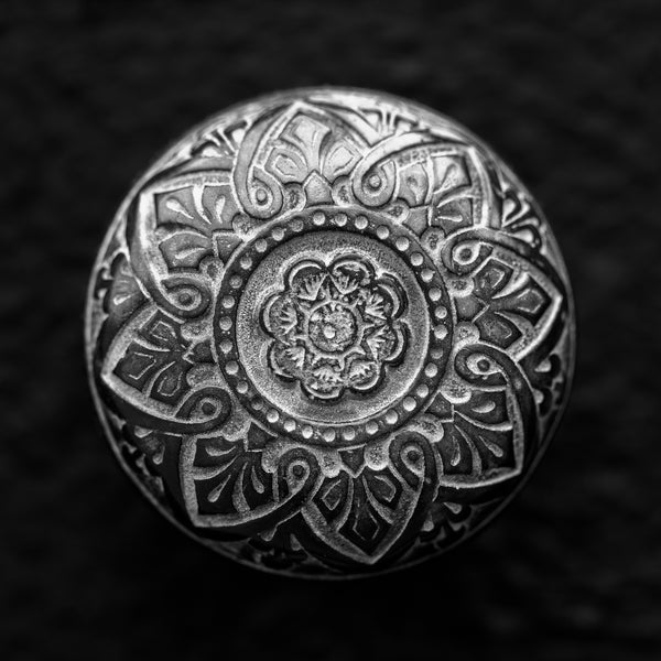 Black and white photograph of the designs on an ornate antique brass door knob found on a historic library building in the American Midwest. (Square format)