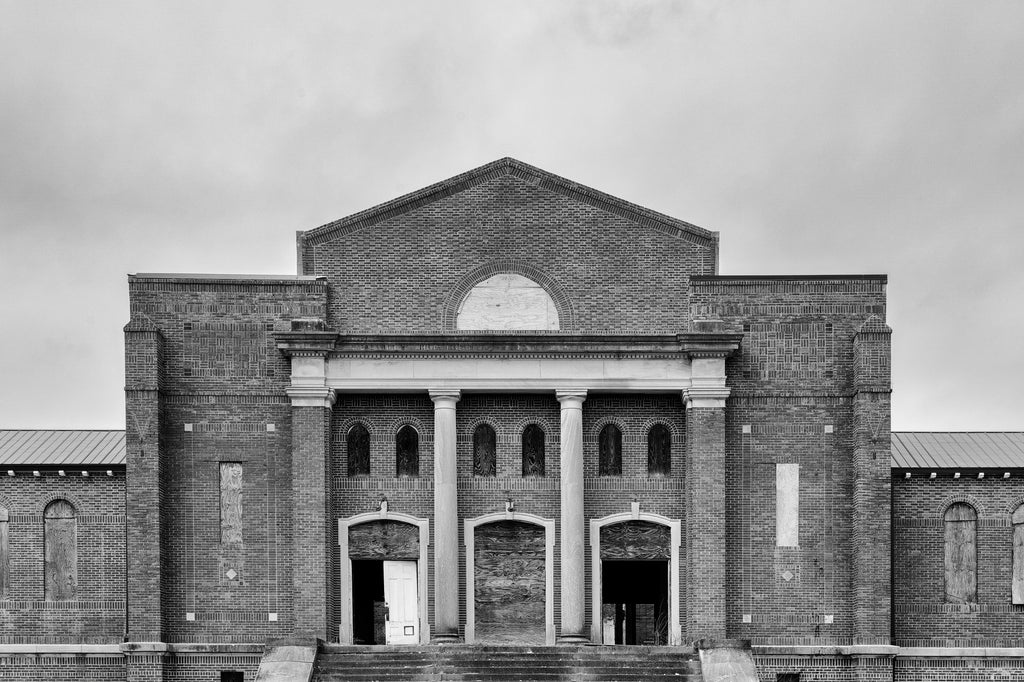 Black and white photograph of a majestic but abandoned building on a vacant college campus in the American South.