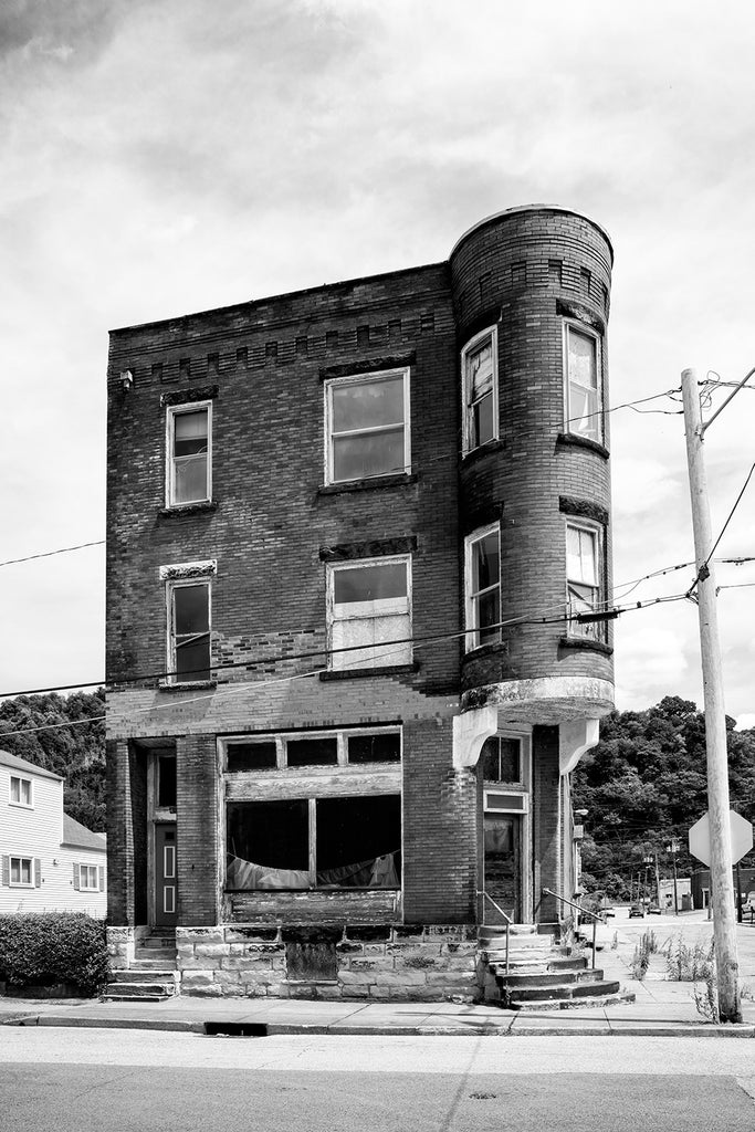 Black and white photograph of an abandoned building in South Wheeling, West Virginia. Built in 1901, it was the location of Holdermann Bros. grocery store in 1919, and later held residential units upstairs.